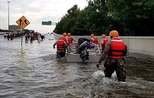 Photo of men helping civilian with boat in flood