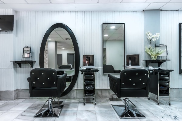 two chairs in front of a mirror inside a hair salon