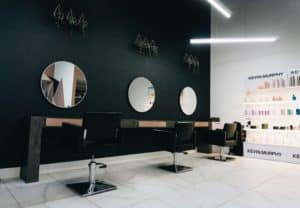 Minimal and modern salon decor ideas, a salon with round mirrors and black walls with decorative plants