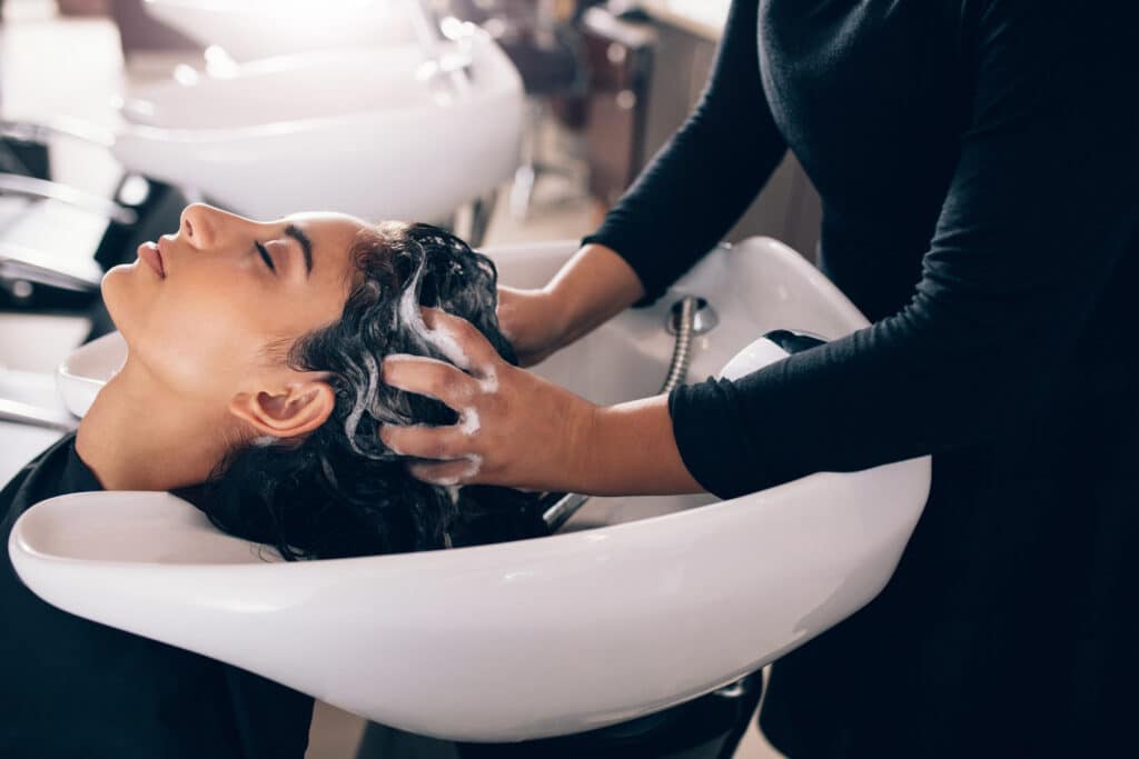 Salon Stylist Washing Client's Hair in Sink