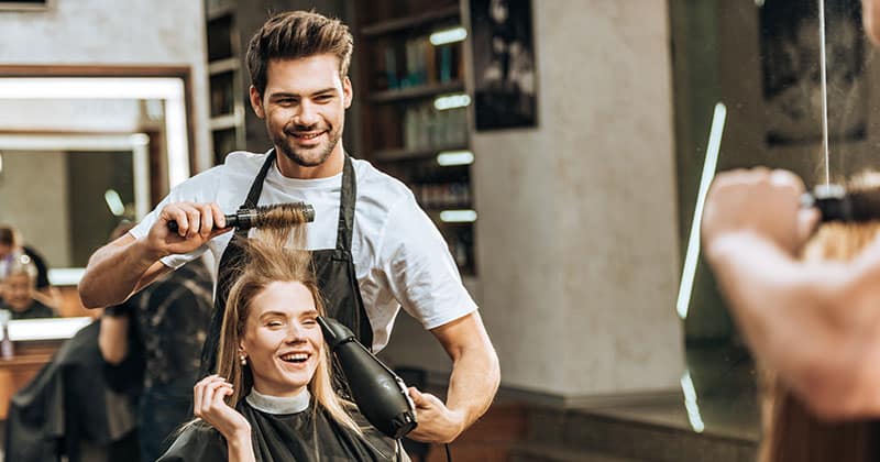 Male stylist drying womans hair