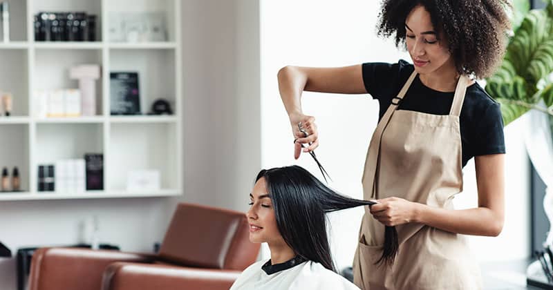 Woman stylist cutting womans hair