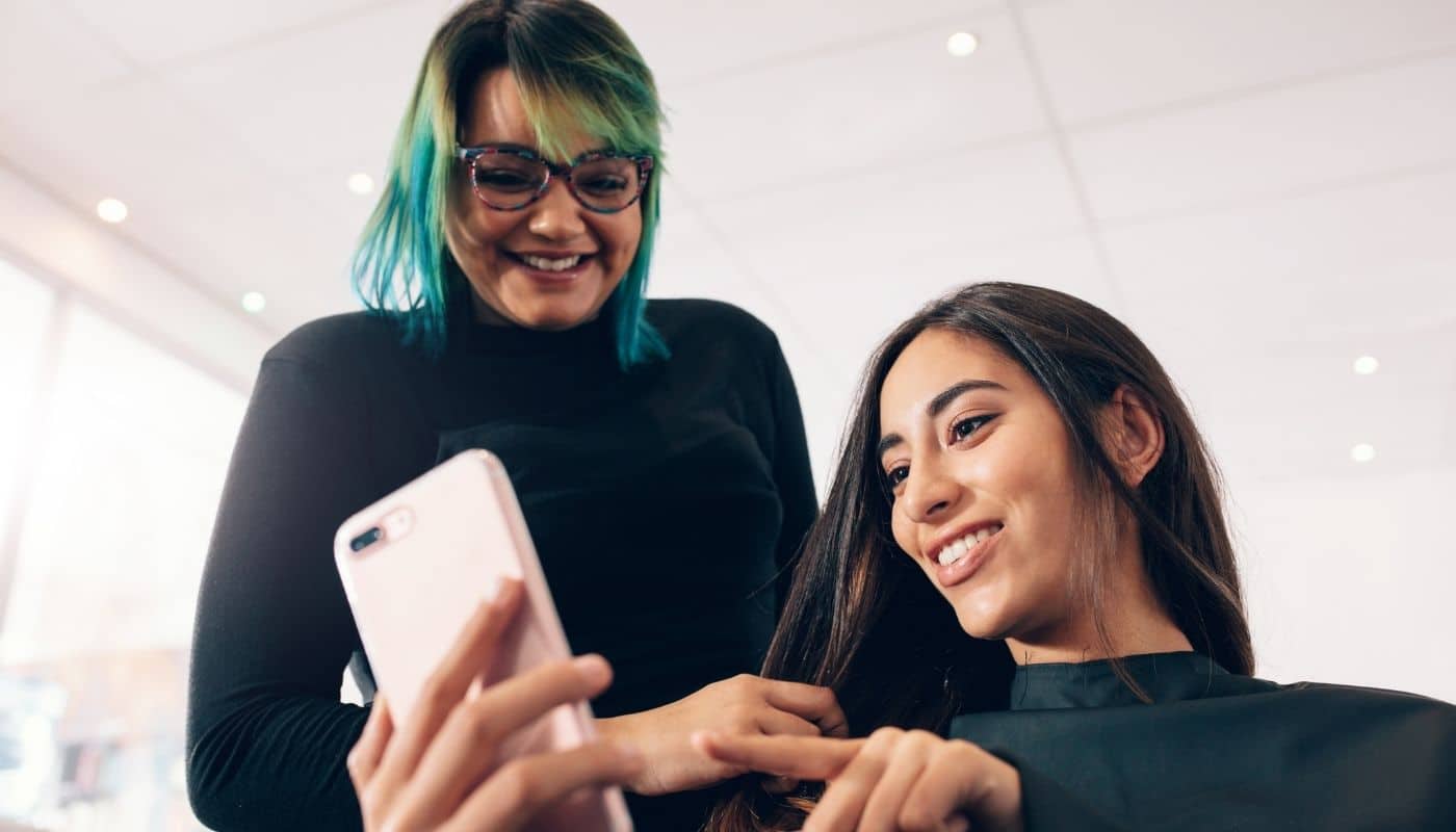 Hair stylist and client reviewing unique salon service ideas on a phone together