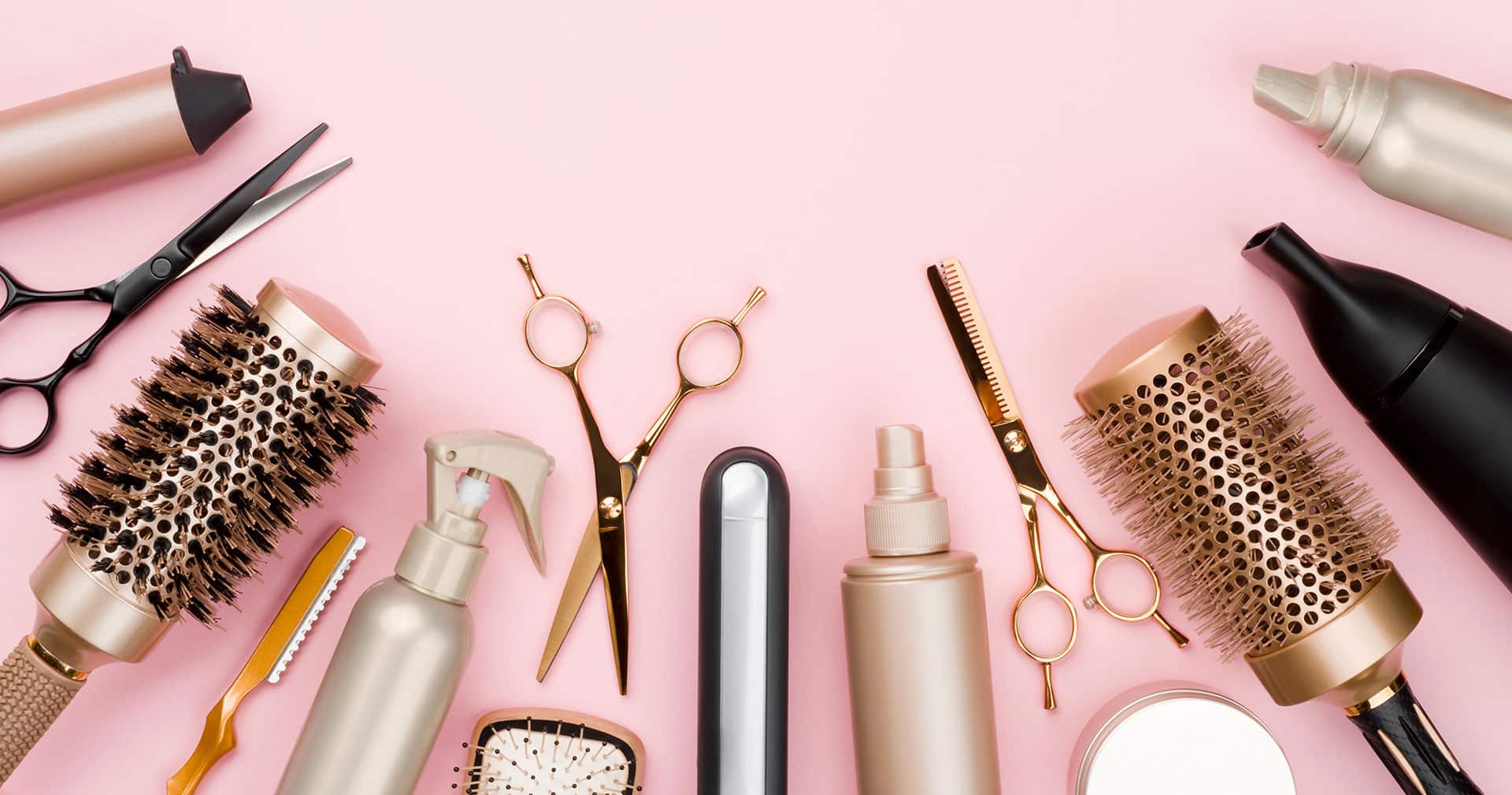 various hair stylists tools on pink background