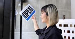 salon owner turning over an open sign on a door