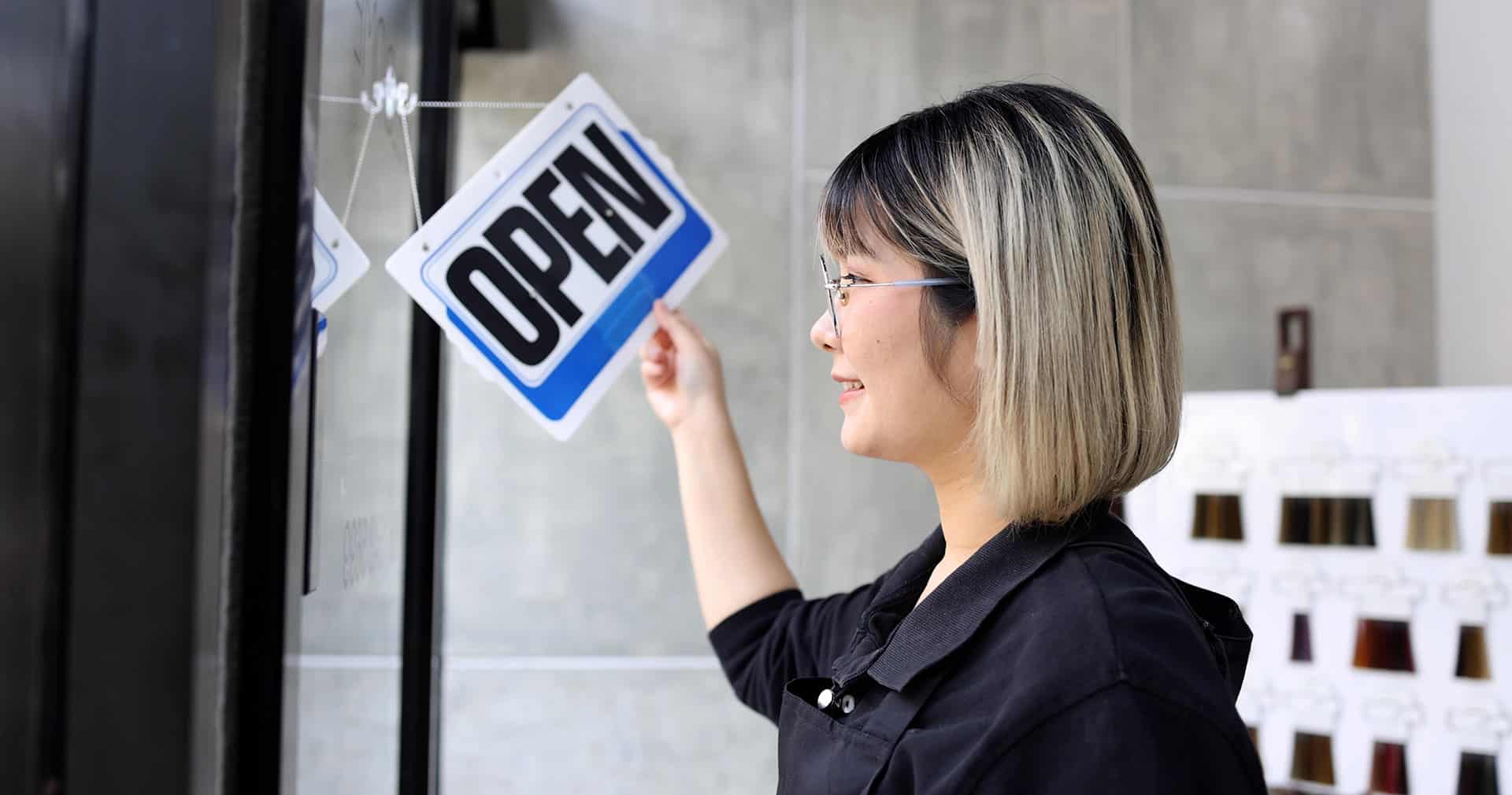 salon owner turning over an open sign on a door