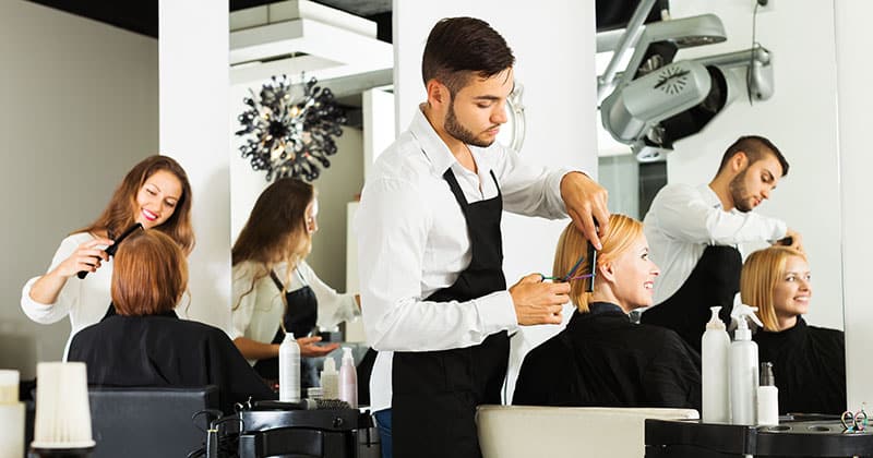two stylists in a salon working at a station while standing next to each other