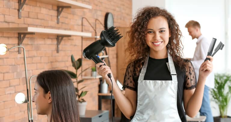 a stylist holding a dryer and a comb