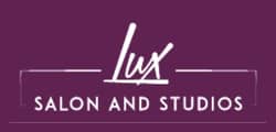 Logo for Lux Salon and Studios, perfect for your next software demo. "Lux" appears in a casual, script font above "SALON AND STUDIOS" in uppercase letters, all set against a sleek purple background.