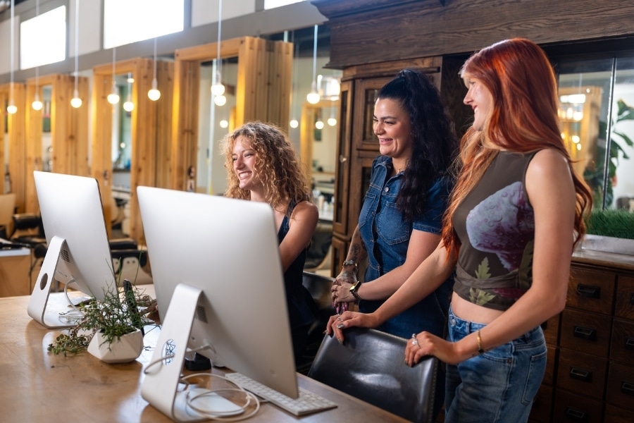 group of salon staff looking at the SalonBiz app on a desktop computer