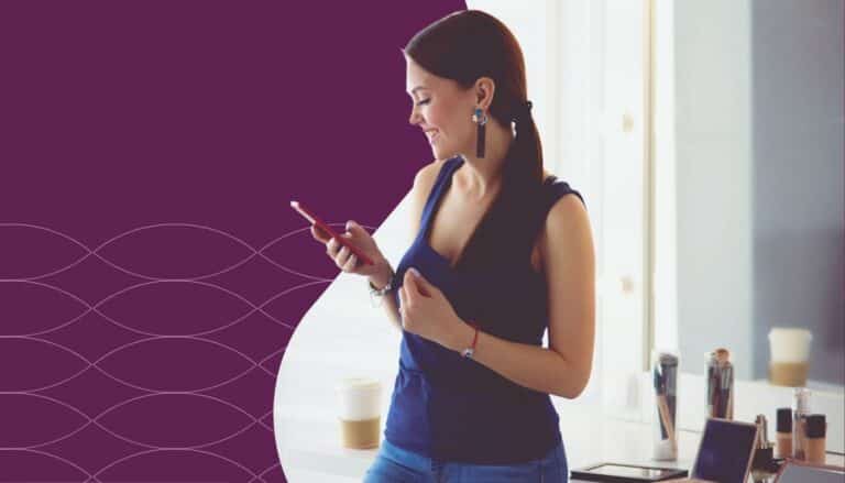 Woman stands in a salon space checking her smartphone while smiling. Beauty products, makeup brushes, and a coffee cup sit on a nearby counter, while a purple branded graphic with a subtle wave pattern frames the image, highlighting salon technology, client communication, and business growth tools.