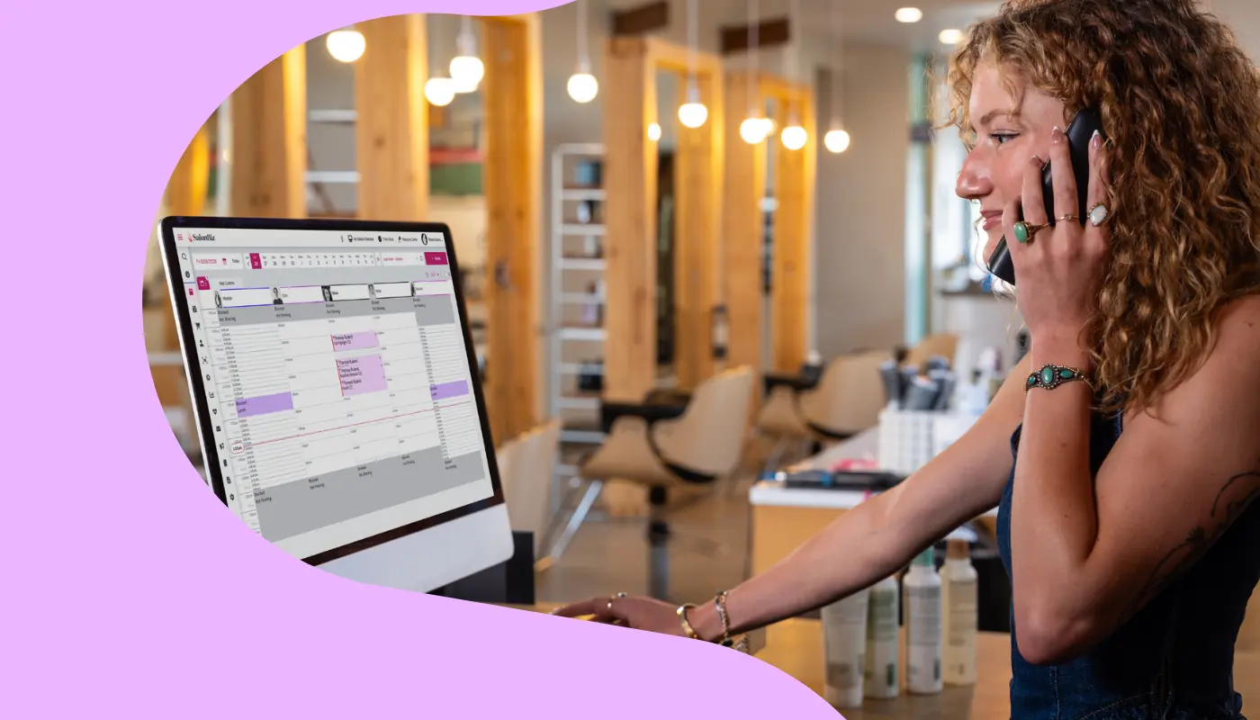 Salon front desk employee on the phone while using a desktop computer