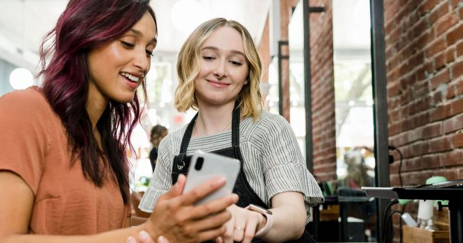 Hair-stylist-and-customer-looking-at-phone