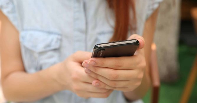 Women standing with Iphone is her hands