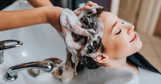 Woman getting hair shampooed at salon