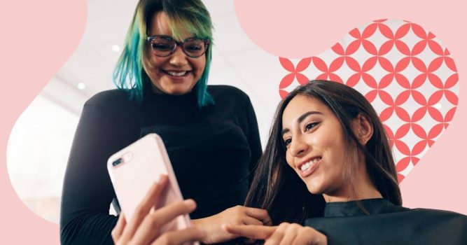 Salon professional and client smile while looking at a smartphone together during a salon appointment. The image features soft pink branded graphics and a patterned accent in the background, highlighting client engagement, personalized service, and the salon experience.